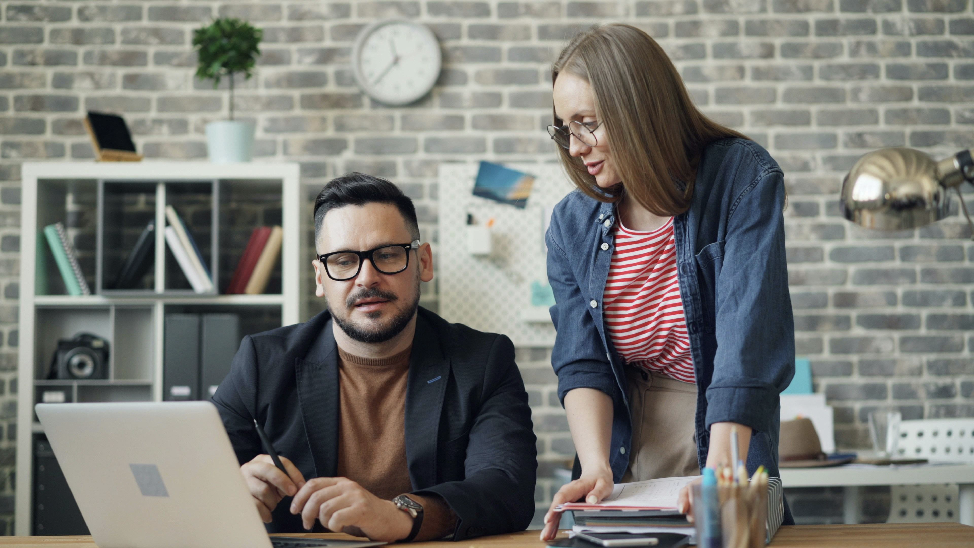Man and woman in consultation at a desk.
