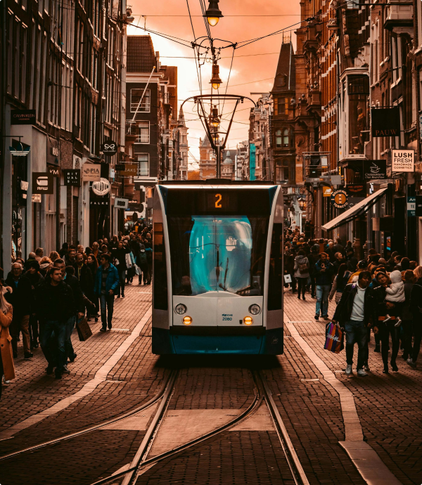 Amsterdamse tram lijn 2 rijdend door een drukke winkelstraat bij zonsondergang.